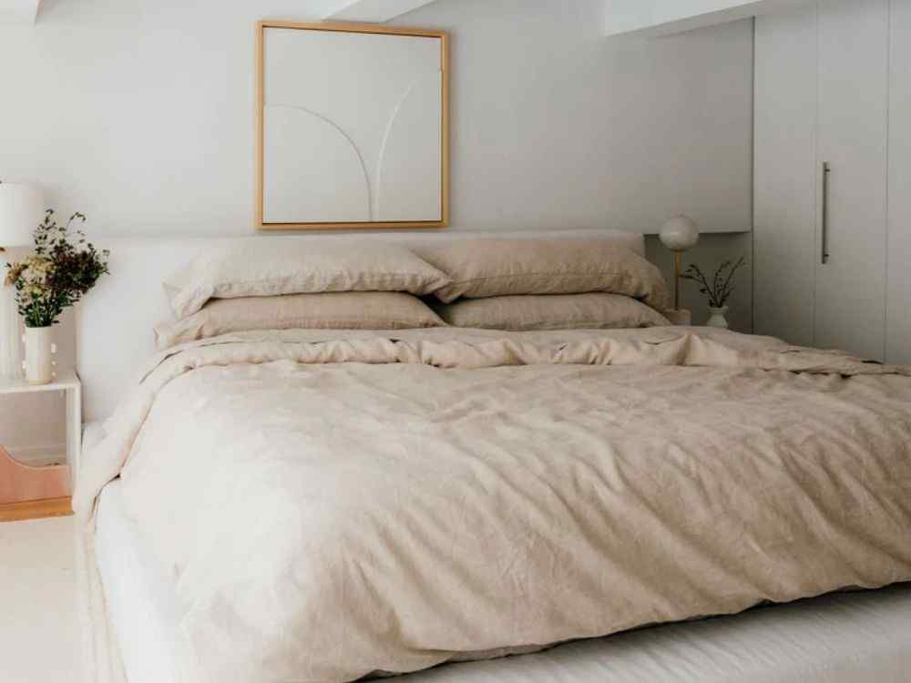 Phòng ngủ tông be sáng với giường đệm dày, trang trí tối giản