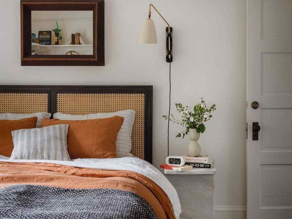 Phòng ngủ vintage tối giản, đầu giường mây tre, chăn cam đất, tường trắng điểm đèn treo retro