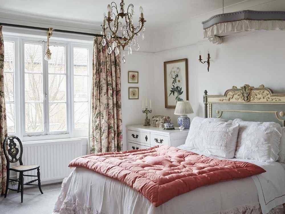 Phòng ngủ vintage tông trắng kem, giường chạm khắc cổ điển, rèm hoa mềm mại, đèn chùm pha lê