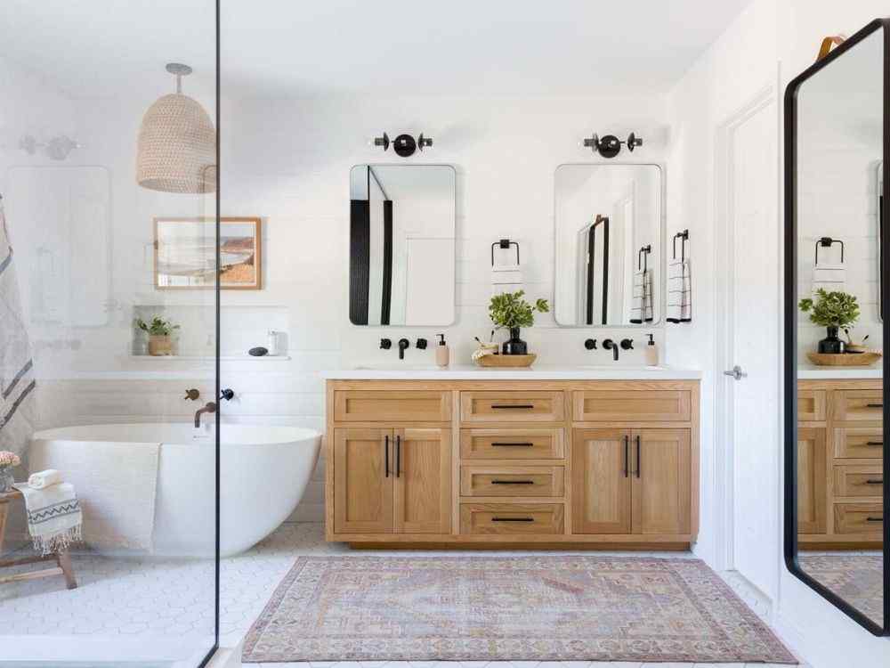 Phòng tắm sáng với bồn tắm độc lập, tủ gỗ lớn, gương đôi