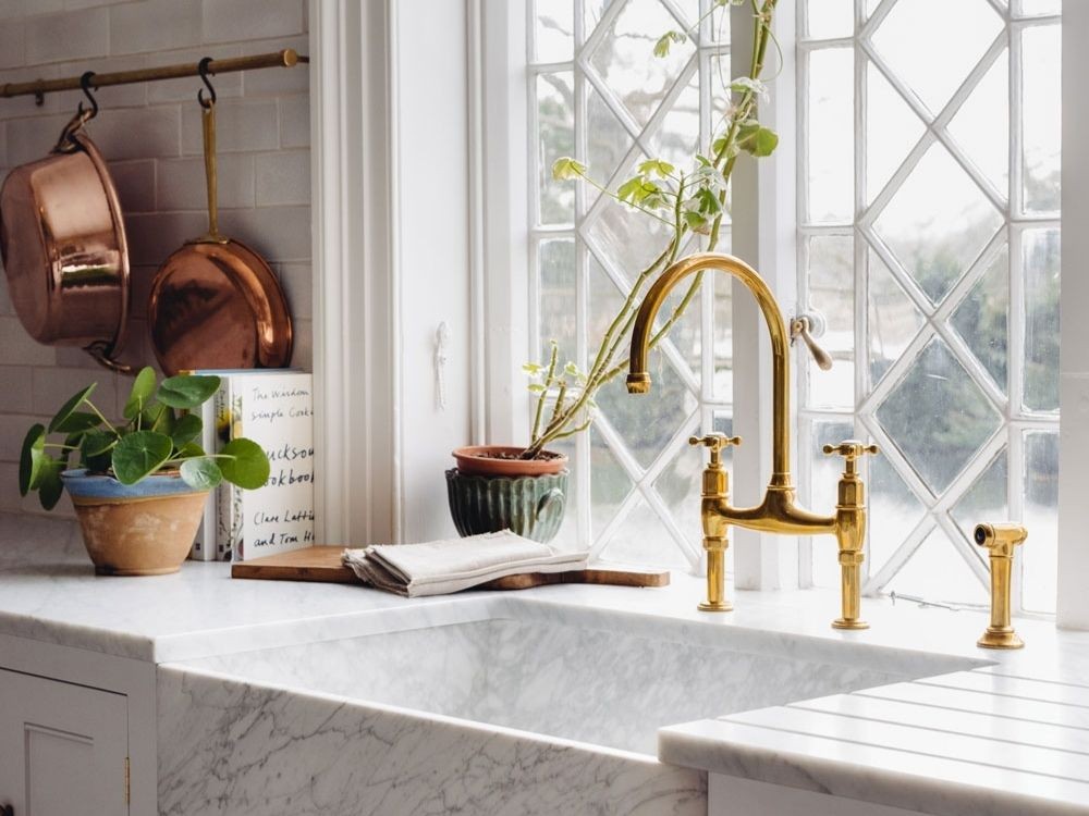 Vòi nước đồng ánh vàng, mặt đá marble trắng, cửa sổ kính hoa văn hình thoi