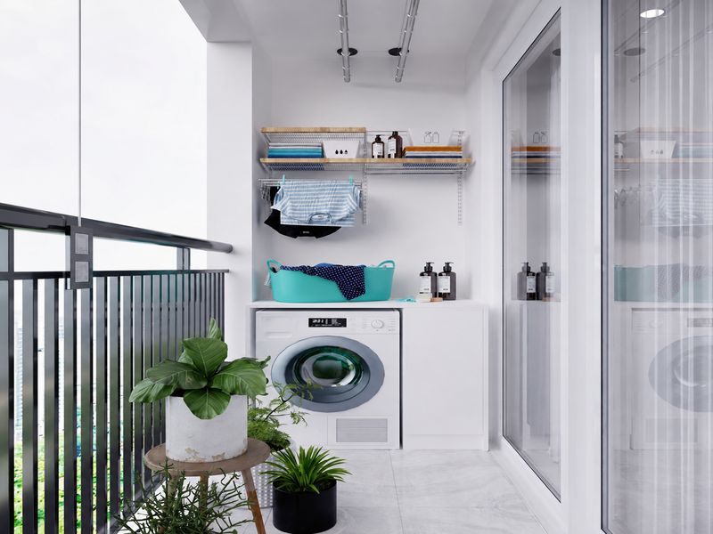 Ban công chung cư 55m2 bố trí máy giặt, tủ chứa đồ, giá phơi và chậu cây cạnh lan can