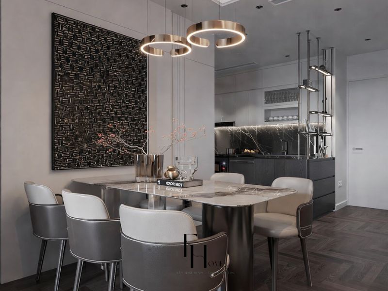 Khu bếp và bàn ăn chung cư 50m2 phong cách Luxury với bàn bầu dục đá cẩm thạch trắng chân thép mạ bạc, bộ đèn thả 3 vòng mạ vàng đồng lệch cỡ và ốp tường sau bếp đá cẩm thạch đen vân trắng