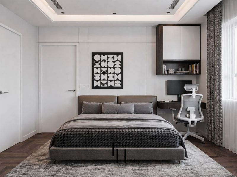 Phòng ngủ chung cư 50m2 phong cách Luxury với trần giật cấp đèn âm trần, giường bọc nỉ nâu đất ấm, tranh hình học đen trắng và góc làm việc tích hợp tủ kệ gỗ óc chó