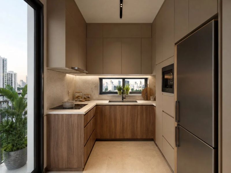 Bếp chung cư 50m2 bố cục chữ L tủ trên be nâu kéo sát trần tủ dưới gỗ óc chó mặt bàn trắng ốp tường sau bếp đá be tủ lạnh inox