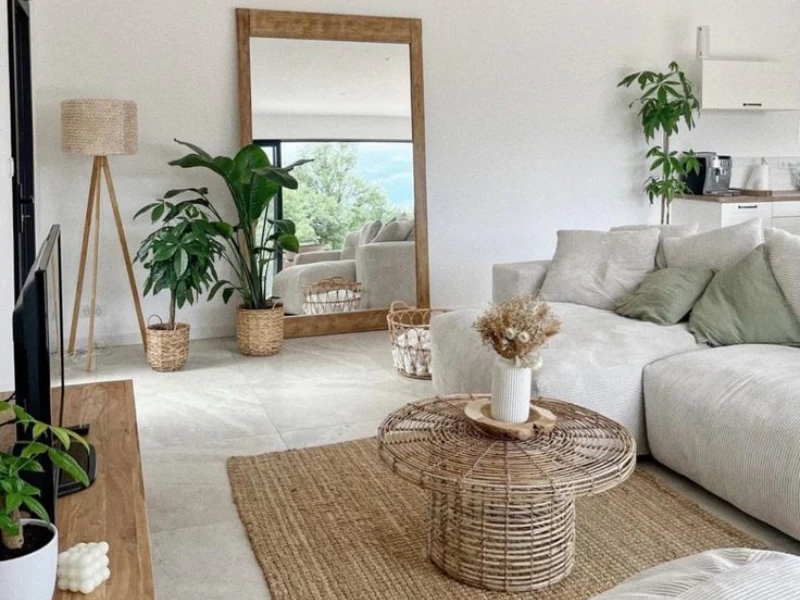 Phòng khách chung cư tối giản với sofa sáng màu gương lớn bàn mây và cây xanh