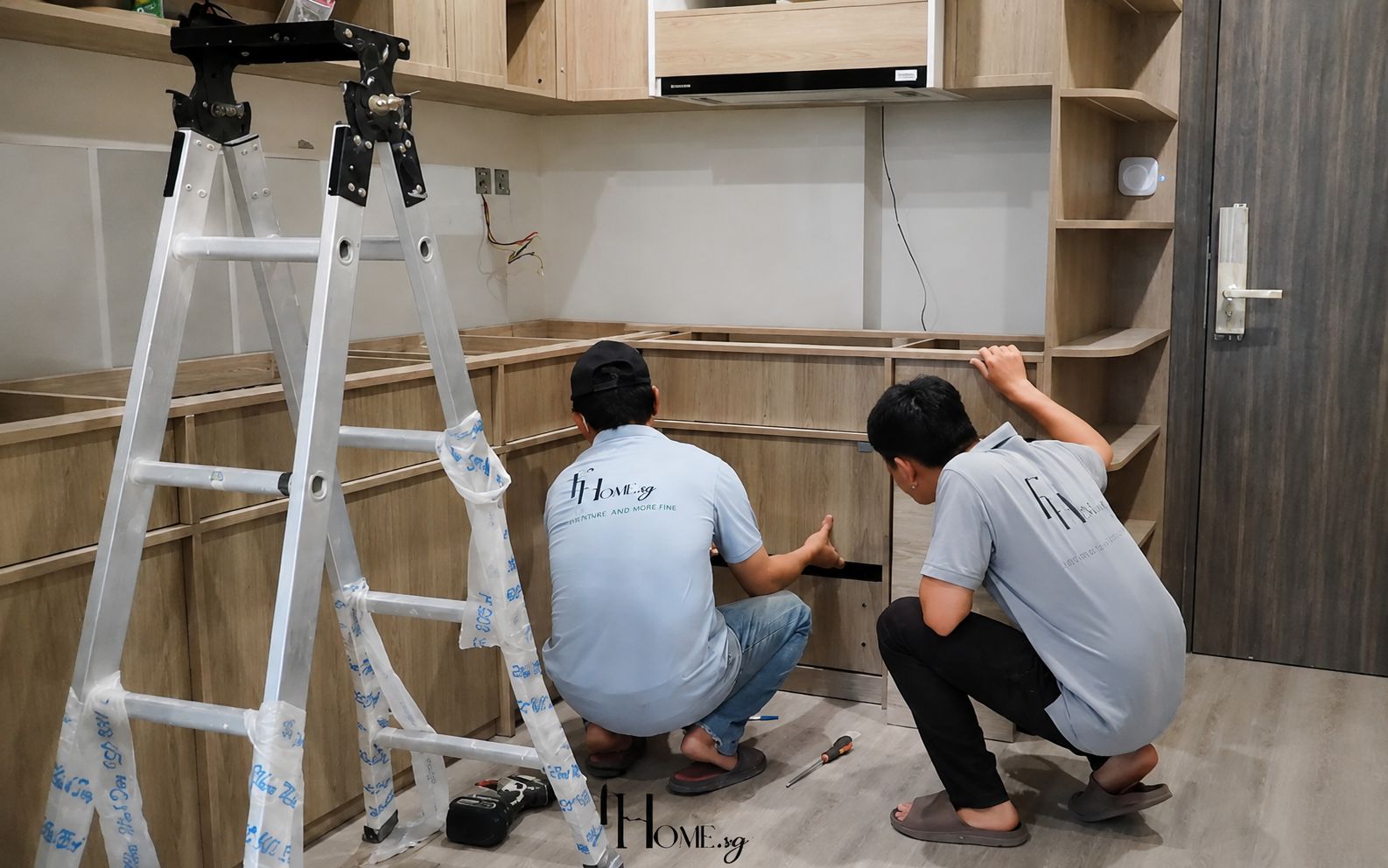 Hai thợ FHome lắp đặt hệ tủ bếp tại công trình
