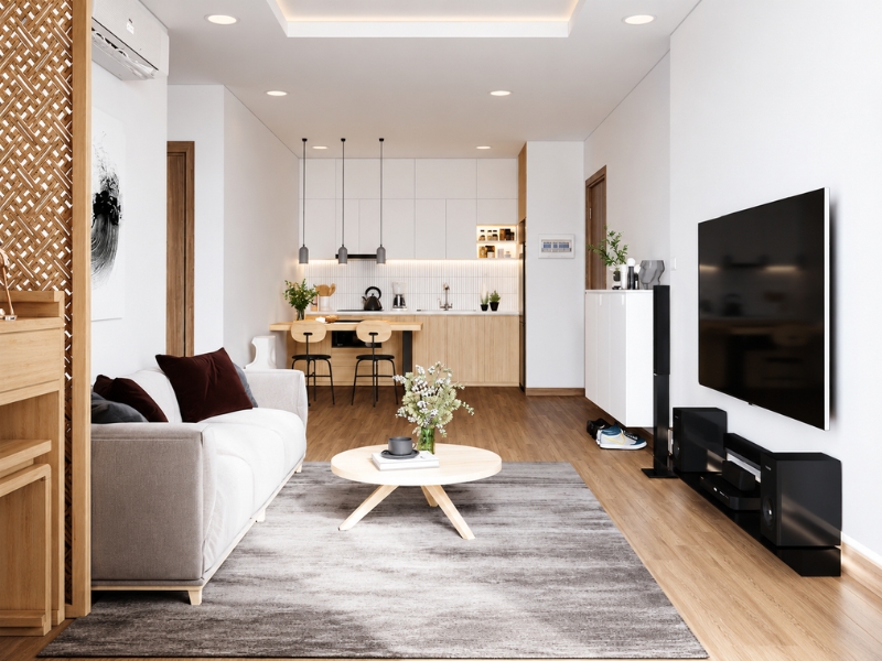 Không gian phòng khách liền bếp phong cách Japandi với sofa sáng màu, bàn trà tròn, tủ gỗ và kệ tivi.