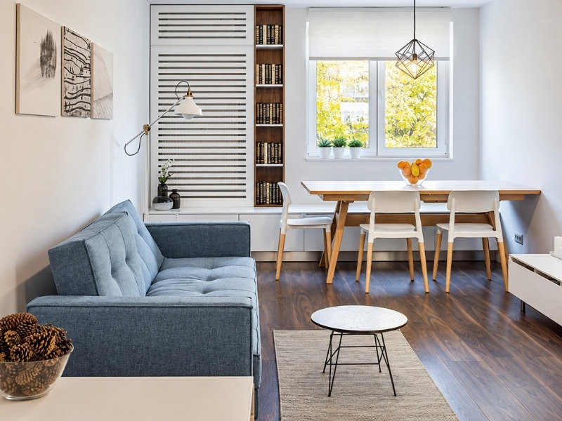 Phòng khách chung cư với sofa xanh, bàn ăn gỗ và cửa sổ đón ánh sáng tự nhiên