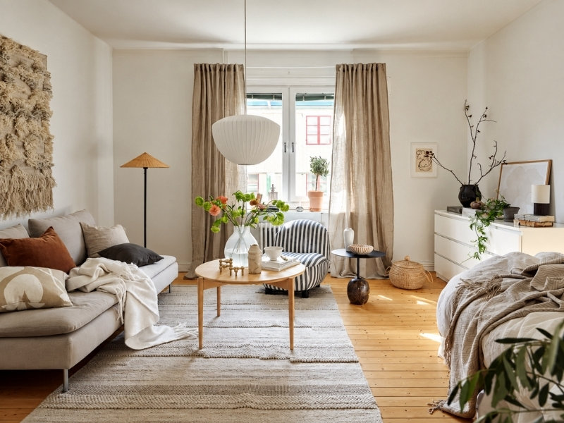 Phòng khách chung cư với sofa be, bàn trà gỗ, thảm sáng màu và cửa sổ lớn