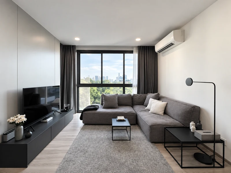 Phòng khách chung cư 40m2 với sofa chữ L màu xám, bàn trà đen và cửa sổ lớn.