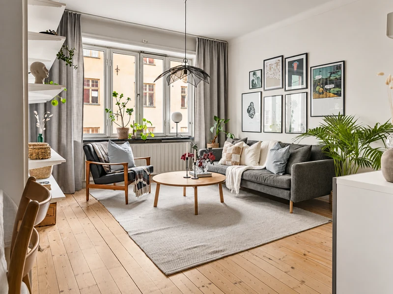 Phòng khách chung cư gam màu trung tính với sofa xám, thảm trải sàn, bàn gỗ và tranh treo tường.