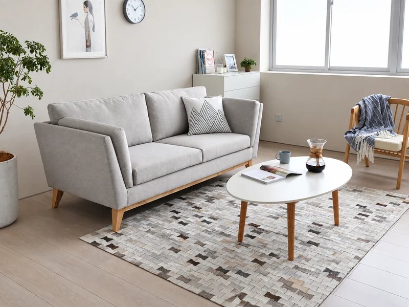 Phòng khách chung cư tối giản với sofa văng màu xám, bàn trà trắng, thảm họa tiết và cửa sổ lớn