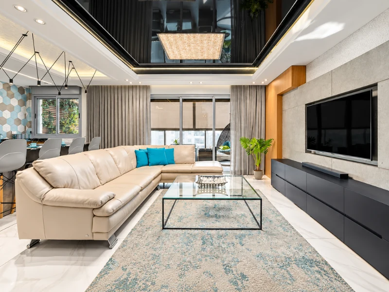 Phòng khách hiện đại với sofa chữ L, bàn trà kính và kệ tivi màu đen.