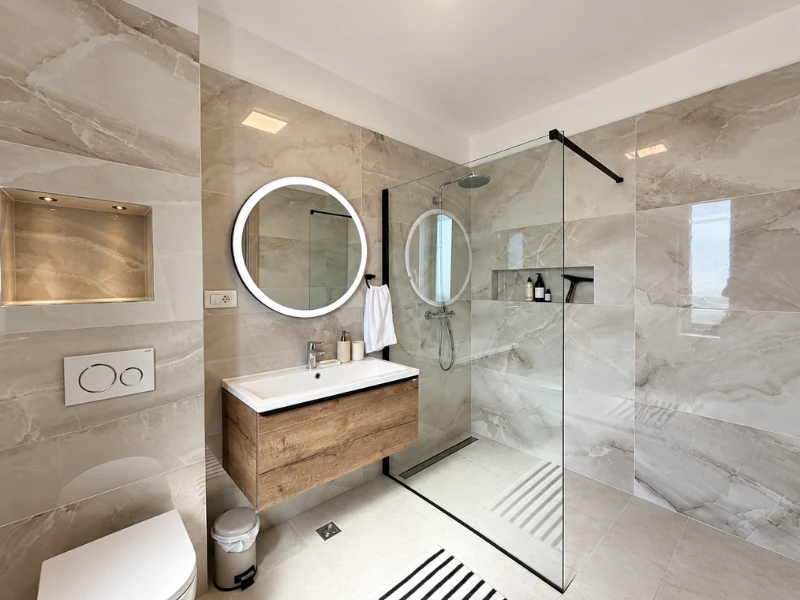 Thiết kế phòng tắm hiện đại với vách kính đứng và tủ lavabo treo tường tinh giản.