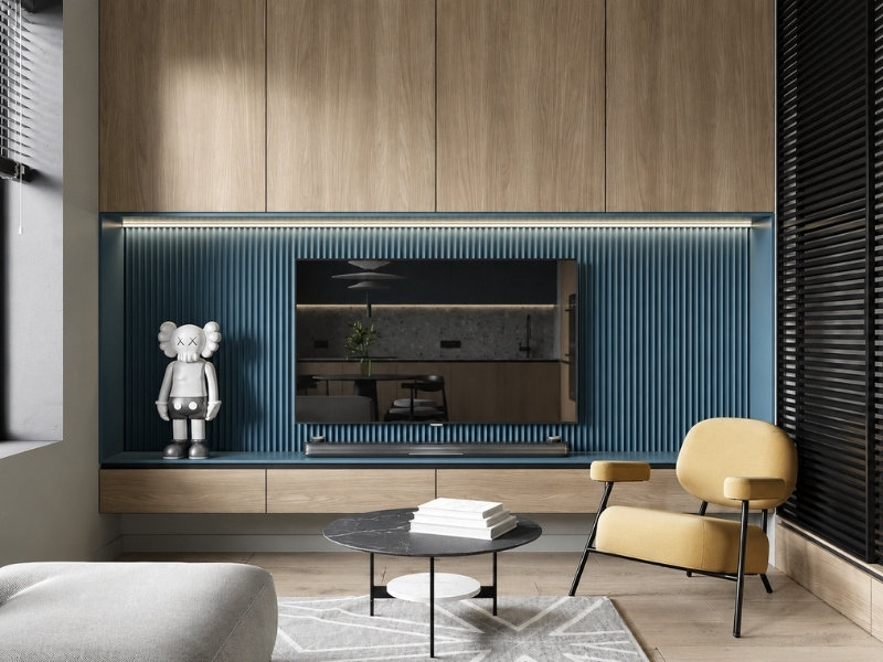 Khu vực tivi căn hộ 40m2 với tủ gỗ kịch trần, vách lam xanh và ghế bành vàng