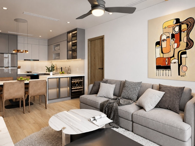Phòng khách liền bếp hiện đại với sofa xám, tủ bếp tối màu và sàn gỗ
