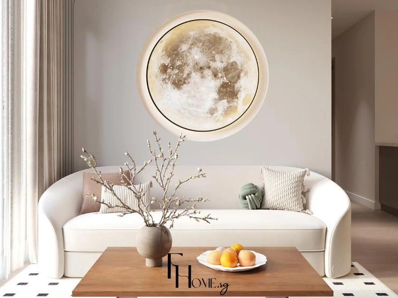 Phòng khách căn hộ tông kem với sofa bo cong vải trắng, đèn tường hình trăng tròn và bàn trà gỗ